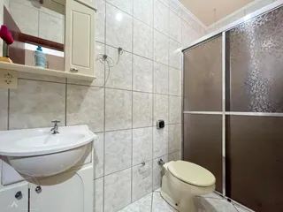 Foto interna de um banheiro com revestimento de azulejos brancos e pia.