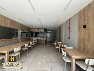 Interior de um espaço com mesas e cozinha em Lajeado.