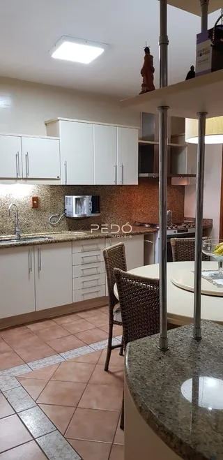 Vista interna de uma cozinha com armários brancos e piso de cerâmica.