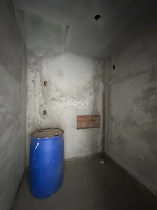 Uma vista interna de um corredor com paredes brancas e acabamento cru.