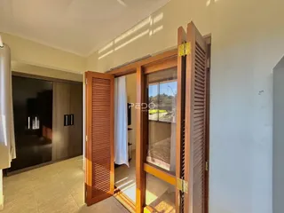 Vista de um corredor interno com portas de madeira e uma porta de vidro.