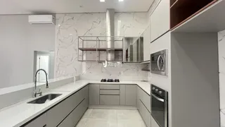 Cozinha moderna com revestimento em mármore branco e armários cinza.