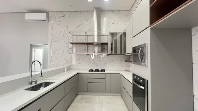 Cozinha moderna com revestimento em mármore branco e armários cinza.