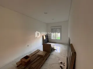 Interior de uma sala com paredes brancas e piso de mármore claro em uma residência.