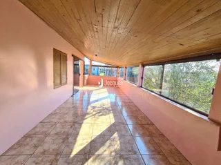 Hall de corredor com piso de cerâmica e teto de madeira em imóvel em Lajeado.