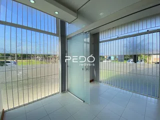 Interior de uma sala com grandes janelas de vidro e piso de cerâmica.
