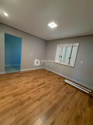 Sala de estar com piso de madeira clara e paredes cinzas.