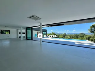 Sala ampla com vista para uma piscina e paisagem verde.
