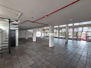 Foto de um grande espaço interno com piso de cerâmica e colunas brancas.