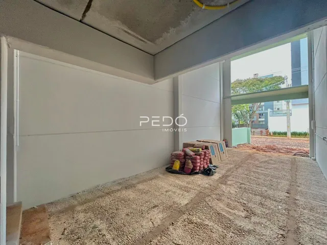 Imagem de uma área interna em construção com paredes brancas e piso de terra.