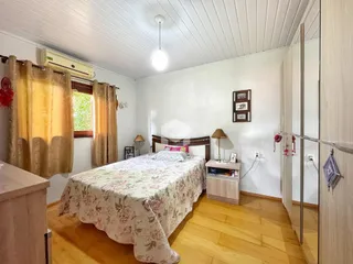 Quarto com piso de madeira e cortinas.