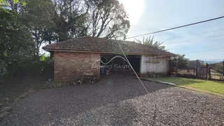 Foto da fachada de uma casa rústica com telhado de telhas e acesso por cascalho.