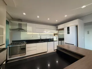 Cozinha moderna com armários brancos e eletrodomésticos de aço inoxidável.