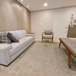 Sala de estar com sofá branco e piso de carpete claro.