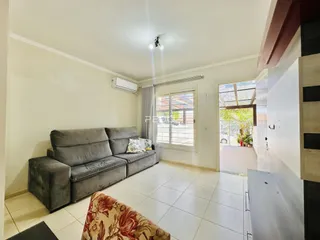 Sala de estar com sofá cinza e piso de cerâmica clara.