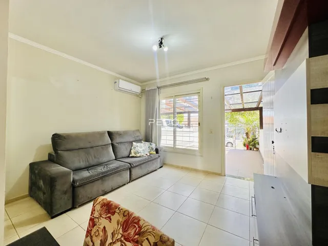 Sala de estar com sofá cinza e piso de cerâmica clara.