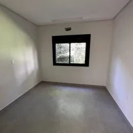 Ambiente interno com paredes brancas e uma janela escura.