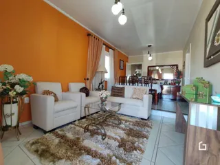Sala de estar com paredes laranjas e móveis brancos.
