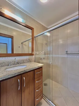 Banheiro com box de vidro e bancada de granito.