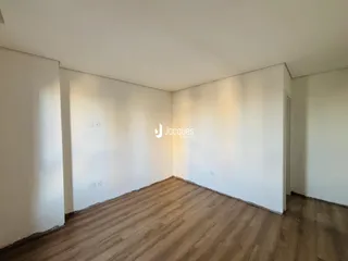 Imagem de um ambiente interno com piso de madeira e paredes brancas.
