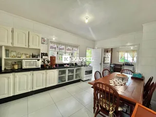 Cozinha com armários brancos e mesa de jantar de madeira em um imóvel.