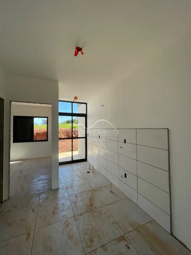 Vista interna de um corredor com piso de cerâmica claro e paredes brancas.