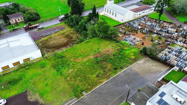 Vista aérea de um terreno com área gramada e estruturas ao fundo.