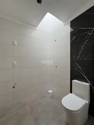 Interior de um banheiro com revestimento cerâmico branco.