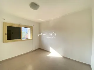 Interior de uma sala com paredes brancas e piso claro.