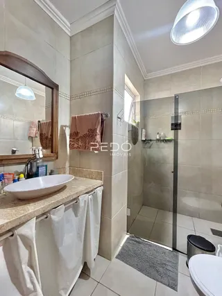 Foto de um banheiro com revestimento de azulejos claros e box de vidro.