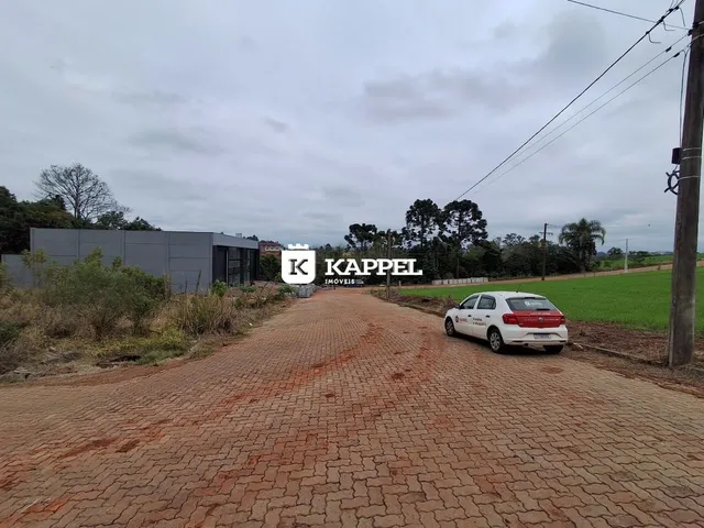 Vista externa de uma propriedade com uma estrada de paralelepípedos e um edifício moderno ao fundo.