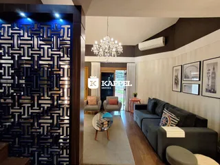 Sala de estar com sofá cinza e piso de madeira, apresentando uma decoração moderna.