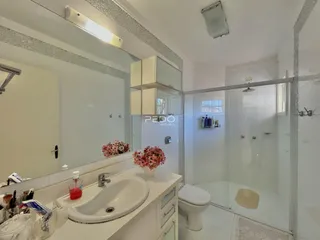 Banheiro moderno com box de vidro e pia branca.