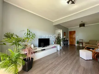 Sala de estar ampla com piso de madeira e plantas decorativas.