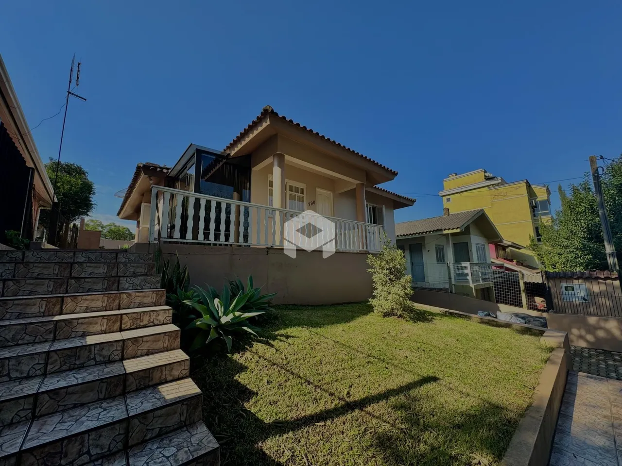 Fachada de uma residência em Lajeado, Brasil, com escadaria de pedra e jardim.