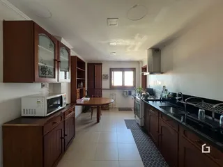 Vista interna de uma cozinha com armários de madeira e piso cerâmico.