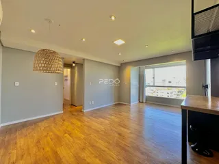 Ambiente interno de uma sala com piso de madeira clara e paredes cinzas.