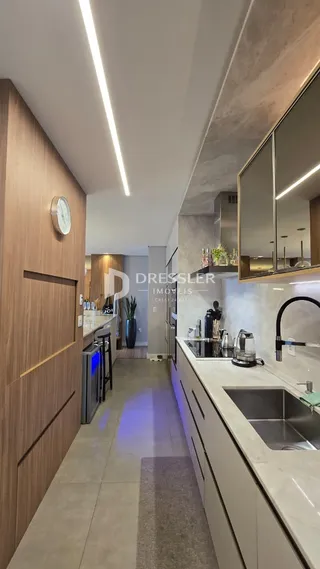 Vista da cozinha moderna com armários de madeira e bancadas brancas.