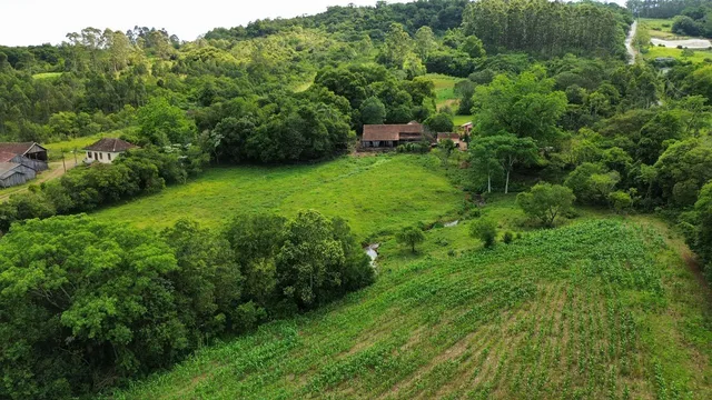 Vista aérea de uma propriedade rural com vegetação exuberante e áreas verdes.
