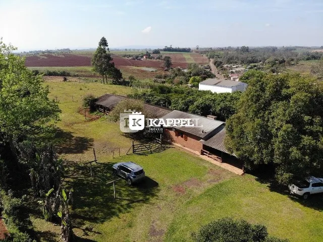 Vista aérea de uma propriedade rural com área gramada e vegetação ao redor.