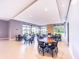 Ambiente amplo com mesas e cadeiras em um espaço iluminado com portas de vidro.