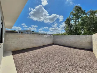 Vista de um terreno com muro de concreto e cascalho.