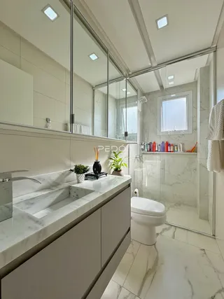Banheiro moderno com revestimento em mármore e piso claro.