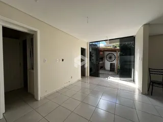 Interior de uma área com piso de cerâmica e portas de vidro que dão acesso ao exterior.