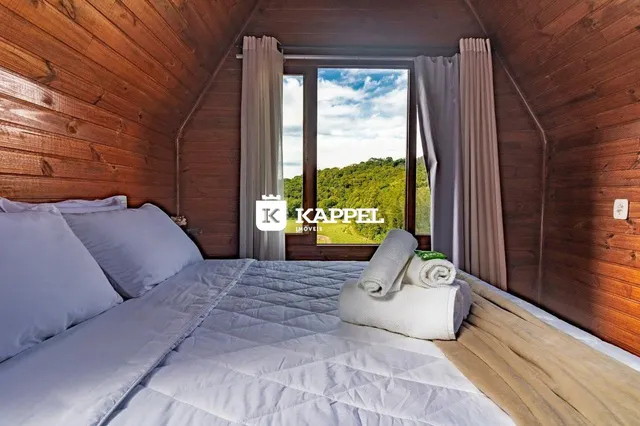 Quarto com paredes de madeira e grande janela com vista para a vegetação externa.