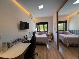 Quarto com duas camas e piso de madeira em um imóvel no Brasil.