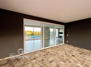 Interior de uma sala com portas de vidro que dão acesso a uma área externa com piscina.