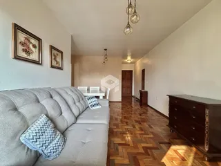 Sala de estar com sofá cinza e piso de madeira no imóvel.