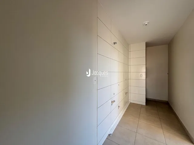 Corredor interno com paredes brancas e piso de cerâmica.