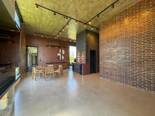 Ambiente interno de uma sala de estar e jantar com paredes de tijolo aparente e piso de porcelanato.